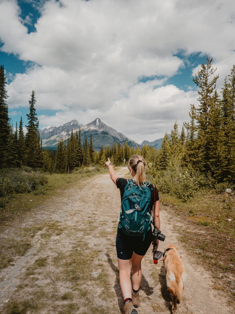 Women hiking with her dog, backpack and camera in the mountains. Photo by Devon Hawkins.